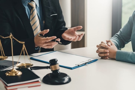 lawyer discussing plea bargains to his client in Grand rapids, MI. A gavel, justice scale, and paperwork are displayed in the image.